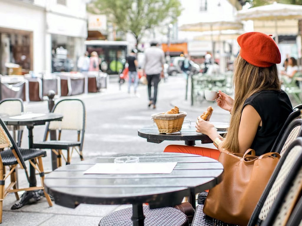 French girl eating baguette and croissant on a terrace in Paris • Paris Tickets